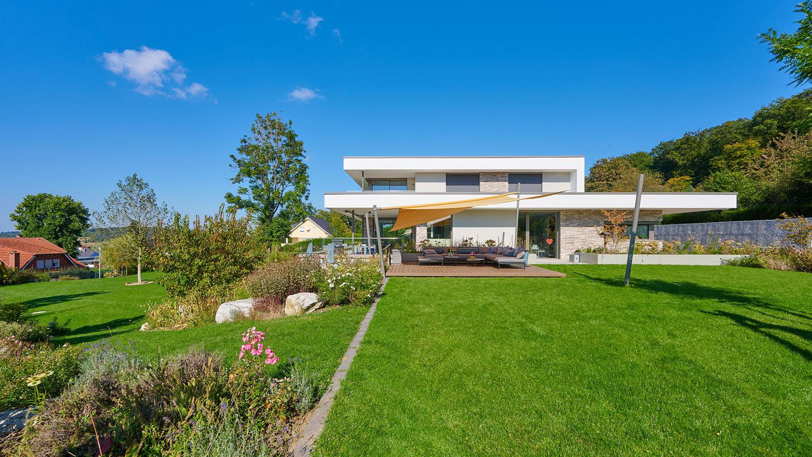 Modernes Wohnhaus mit Sonnensegel und Wildblumen-Beet — Wohnprojekt Hero — Ullrich Gärten