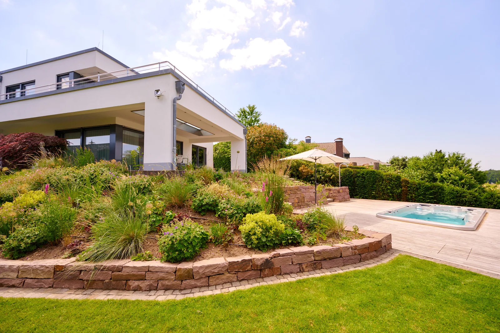 Terrassengarten: moderne Villa mit Natursteinterrassen und Gartenanlage