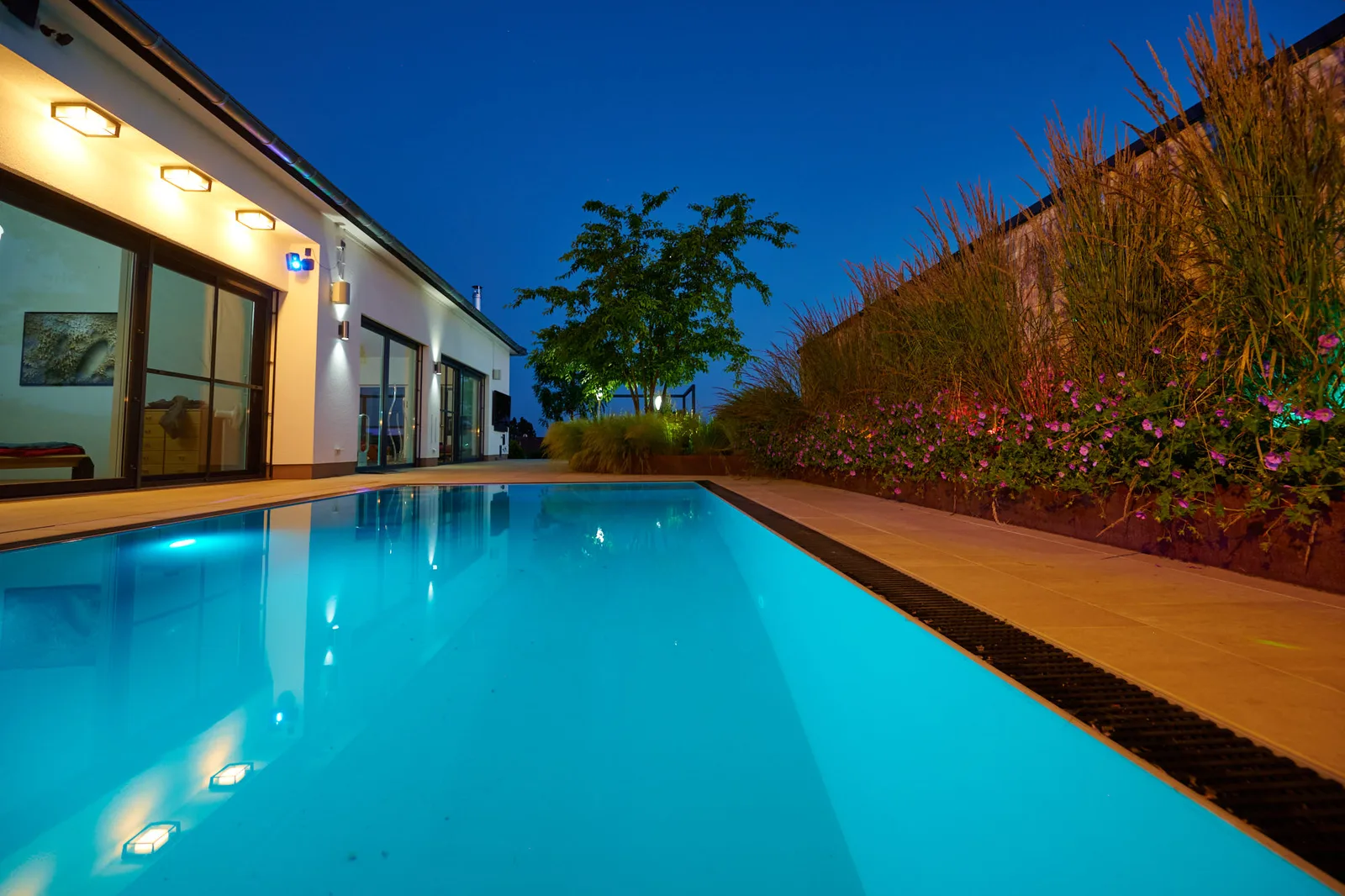 Wellnessgarten: Pool mit moderner Villa in der Dämmerung