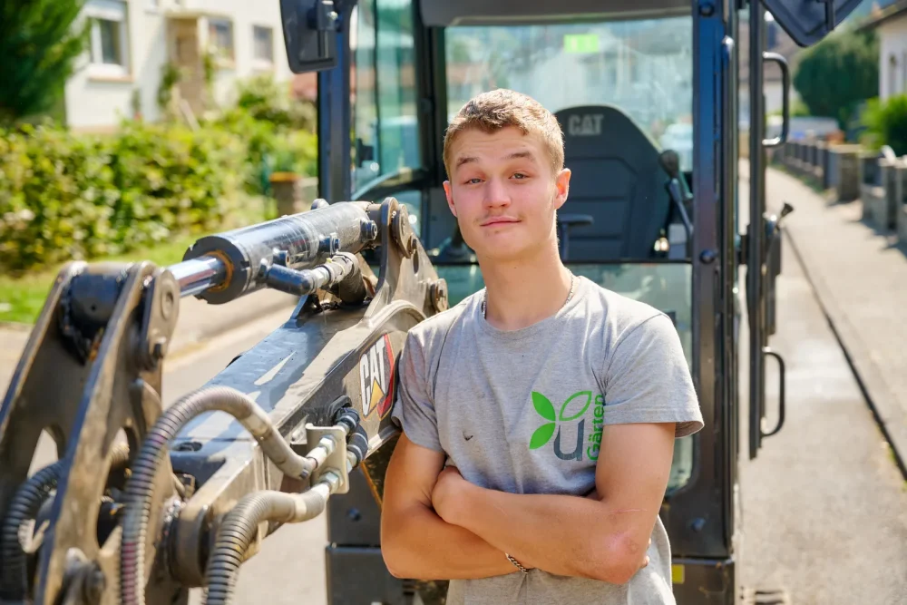 Karriere: junger Mitarbeiter vor dem Bagger